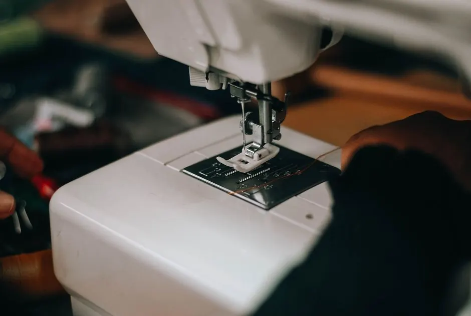 Detailed close-up of hands using a sewing machine, focusing on the needle and fabric.