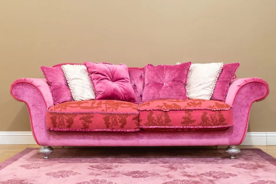 Elegant pink sofa with plush pillows against a brown background, adding a pop of color to any room.